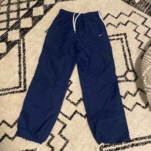 Nike Nylon pants with ankle zipper and white strips down each hip. Draw string